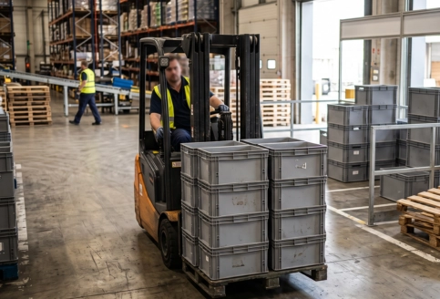 Reusable plastic crate with reinforced handles, ventilated sides, and stackable base design.